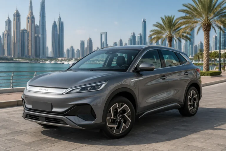 Grey BYD Atto 3 2024 parked along a scenic Dubai waterfront with palm trees and skyscrapers behind.