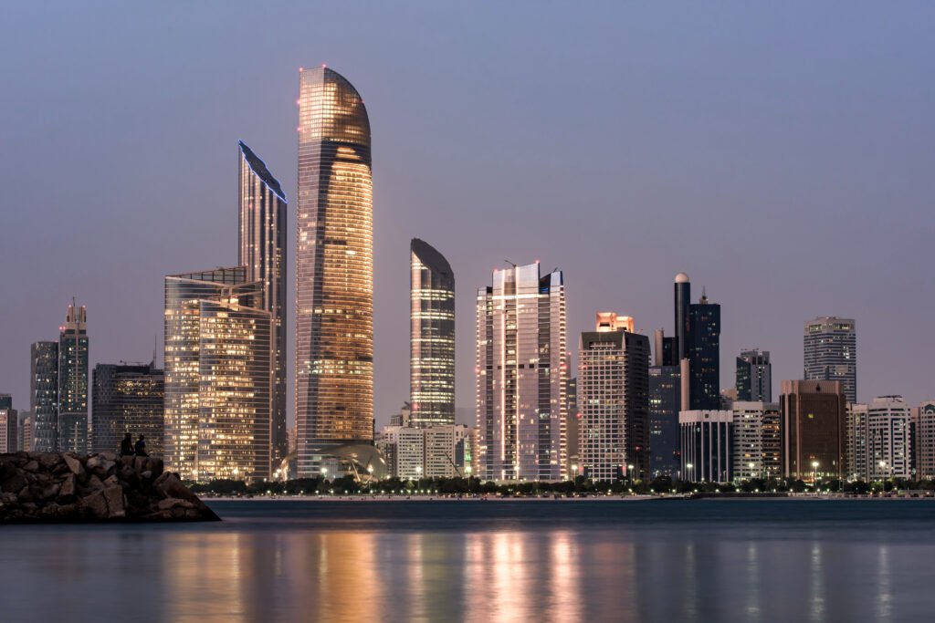 Abu Dhabi skyline at dusk with lit skyscrapers, ideal backdrop for luxury car rental with driver for Doha travelers in UAE.jpg